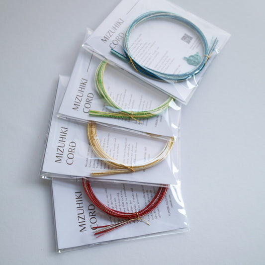 Mizuhiki cord packaging with colorful cords on a light gray background