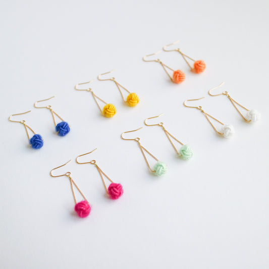 Colorful earrings with pom-pom ends on a light gray background