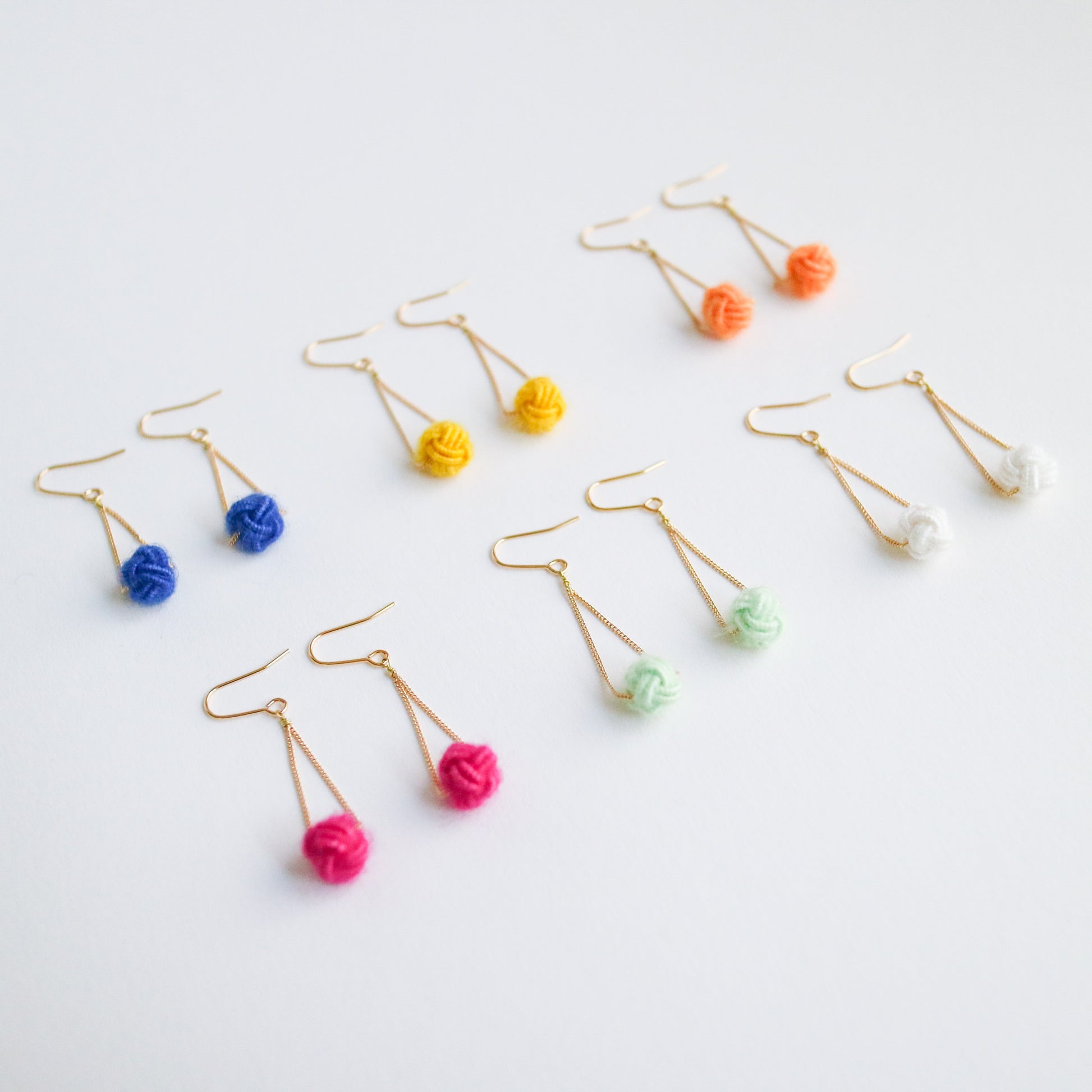 Colorful earrings with pom-pom ends on a light gray background